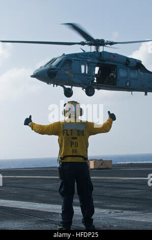 Un avion de la Marine américaine des signaux à un directeur MH-60S Knight Hawk hélicoptère de combat avec la mer de l'Escadron (HSC) 23 au cours d'un ravitaillement vertical en mer avec le navire de soutien de combat rapide USNS Bridge (T-AOE 10) sur le pont de porte-avions USS Carl Vinson (CVN 70) dans l'océan Pacifique le 22 décembre 2011. Le Carl Vinson et Carrier Air Wing (CVW) 17 étaient en cours sur un déploiement de l'ouest du Pacifique. (U.S. Photo par marine Spécialiste de la communication de masse Seaman Apprentice Dean M. Cates/libérés) un avion de la Marine américaine des signaux à un directeur MH-60S Knight Hawk hélicoptère de combat avec la mer de l'Escadron (HSC) du 23 Banque D'Images