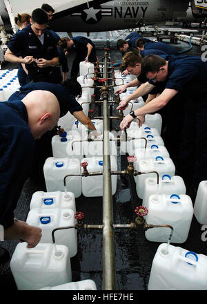 Des marins du département des réacteurs et de la division des réparations à bord de l'USS Abraham Lincoln remplissent des cruches d'eau purifiée pour l'acheminement de secours humanitaires dans les régions touchées par le tsunami à Sumatra, en Indonésie, à l'aide d'hélicoptères de la deuxième Escadre aérienne du transporteur aérien. Banque D'Images