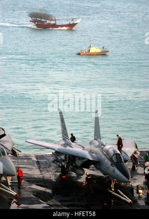 031227-N-9742R-001 Manama, Bahreïn (31 déc. 27, 2003) -- d'envol le personnel procède à l'entretien d'un F-14 Tomcat affecté à l'Escadron de chasse Deux ÓCheckmatesÓ de One One (FV-211) sur le site de l'envol du USS Enterprise (CVN 65), tandis qu'une patrouille côtière et de la Marine américaine voile maintient un périmètre de sécurité autour du porte-avions. L'entreprise et de l'Escadre aérienne de transporteur un (CVW-1) sont actuellement déployés à l'exécution des missions dans le cadre de l'opération Iraqi Freedom et la poursuite de la guerre contre le terrorisme. U.S. Navy photo by Photographer's Mate Airman Milosz Reterski. (Libéré) US Navy 031227-N-9742R-00 Banque D'Images