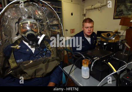 040202-N-9288T-045 à bord de l'USS Vincennes (CG 49) Feb 2, 2004 Incendie 1ère classe Controlman Ð Ritchie Andrews, de Laurelton, N.Y., a un test effectué sur son MCU-2/P masque à gaz alors que les pertes de 3e classe Controlman Travis Ross, de Delavan, au Wisconsin, surveille les lectures sur l'ADT-99M testeur de respirateur à bord du croiseur lance-missiles USS Vincennes (CG 49). L'appareil émet une vapeur d'huile minérale à travers le tuyau à boire sur le masque à gaz, et détecte si une vapeur est présent dans la rétention plastique, indiquant une mauvaise étanchéité du masque à gaz. Vincennes participe à Multi-Sail, un combat readin Banque D'Images