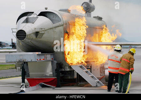 040303-N-5821W-001 Naval Air Station (RNA) de Sigonella, en Sicile (Mar. 3, 2004) - Ron Hall, de la base aéronavale de Sigonella (NAS) Fire Department Chef de bataillon, et l'Aviation maître de Manœuvre 1re classe Stephen Mark, NAS Sigonella Fire Department assistant agent de formation, une bataille avec le feu alors que la formation d'un formateur les incendies d'aéronefs (MAFT) sur les stations la ligne de vol. Le service d'incendie de NAS a récemment obtenu le système pour améliorer le système de formation. Le MAFT peut simuler des incendies de moteur de roue, les incendies, les feux de l'intérieur, et des éclatements de pneumatiques. Sigonella NAS fournit un soutien logistique aux sixième commandant F Banque D'Images