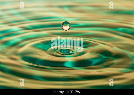 Goutte d'eau et les vagues sur l'eau avec un fond vert. Banque D'Images