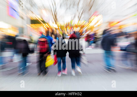 Les gens à pied dans la ville avec marché de Noël à l'arrière-plan, photo faite avec effet de zoom Banque D'Images