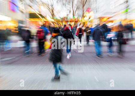 Les gens à pied dans la ville avec marché de Noël à l'arrière-plan, photo faite avec effet de zoom Banque D'Images