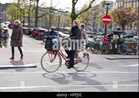 Un cycliste féminin sur la rue à Amsterdam, Hollande, Pays-Bas. Il y a environ un million de bicyclettes. Banque D'Images