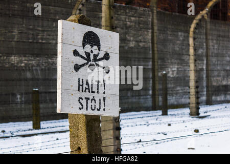 Panneau d'avertissement vu en dehors d'un corps de garde et le bloc 11 d'Auschwitz I, juste avant le fil de fer barbelé électrifié, clôture de périmètre. Banque D'Images