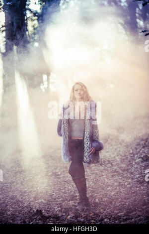 Modélisation photographique comme une carrière au Royaume-Uni : un jeune de 20 ans, slim woman femme fille avec de longs cheveux blonds marcher seule par elle-même dans les bois sur une chaude après-midi d'automne lumineux Banque D'Images