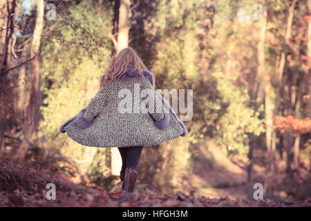 Modélisation photographique comme une carrière au Royaume-Uni : un jeune de 20 ans, slim woman femme fille avec de longs cheveux blonds marcher seule par elle-même dans les bois sur une chaude après-midi d'automne lumineux Banque D'Images