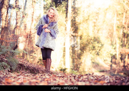 Modélisation photographique comme une carrière au Royaume-Uni : un jeune de 20 ans, slim woman femme fille avec de longs cheveux blonds marcher seule par elle-même dans les bois sur une chaude après-midi d'automne lumineux Banque D'Images