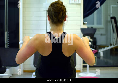 Woman working out ses muscles du dos et des bras avec la poulie à la salle de sport. Banque D'Images