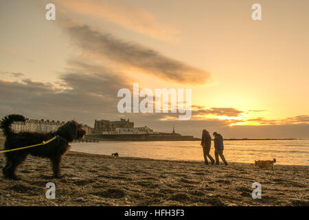 Pays de Galles Aberystwyth UK, New Years Eve, samedi 31 décembre 2016 UK weather : personnes marchant sur la plage au coucher du soleil sur la mer à Aberystwyth, sur la côte ouest du pays de galles sur le dernier jour de l'année. - La météo dans l'ouest a été clair, contraste fortement avec l'épais brouillard qui couvre une grande partie du sud-est de l'Angleterre photo : Keith Morris / Alamy Live News Banque D'Images