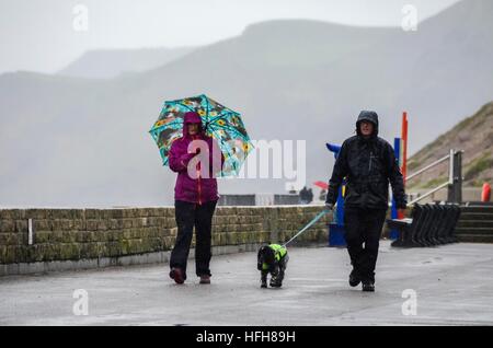 À l'Ouest, Dorset, UK. Le 31 décembre 2017. Météo britannique. Les promeneurs de chiens sur la promenade de West Bay, dans Dorset sur un après-midi pluvieux le jour du Nouvel An. Photo : Graham Hunt/Alamy Live News. Banque D'Images