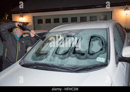 Le dégivrage du pare-brise de voiture personne avec les mots raclés à froid dans la glace sur le pare-brise, Flintshire, au nord du Pays de Galles Banque D'Images