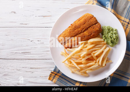 Anglais : aliments à frire poisson frit avec des frites et de la purée de pois sur une plaque horizontale vue du dessus. Banque D'Images