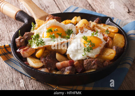 Pommes de terre frites tyrolien avec de la viande, le lard et les oeufs dans une casserole close-up horizontale. Banque D'Images