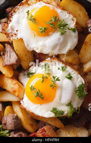 Pommes de terre sautées avec de la viande, du bacon et des œufs. macro vue verticale de l'arrière-plan au-dessus Banque D'Images