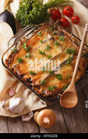 Moussaka grecque close up dans le plat de cuisson avec les ingrédients sur la table. La verticale Banque D'Images