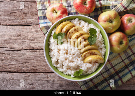 Riz aux pommes caramélisées Dans un bol et les pommes fraîches sur une table horizontale vue du dessus. Banque D'Images