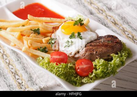 Le déjeuner traditionnel : un steak juteux, œuf frit et frites sur une plaque horizontale de près. Banque D'Images