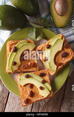 Sandwich sain avec du beurre d'arachide, les avocats et les raisins secs close-up vertical Vue de dessus. Banque D'Images