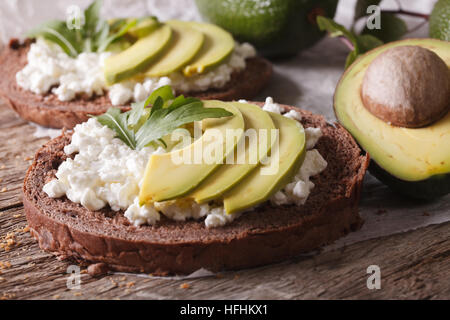 Sandwichs sains avec avocat, fromage à la crème et à la roquette sur la table horizontale. Banque D'Images