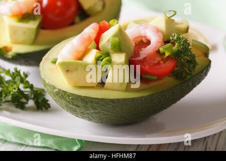 Avocat farci aux crevettes et salade de tomates macro sur une plaque horizontale. Banque D'Images