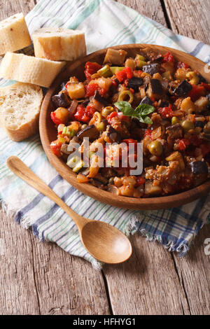 La cuisine sicilienne : Caponata aubergines avec gros plan sur une plaque de bois. De style rustique, vertical Banque D'Images