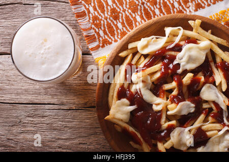 Alimentaire canadien : bière et frites avec sauce close-up sur la table horizontale Vue de dessus. Banque D'Images