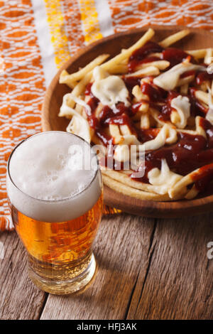 Alimentaire canadien : bière et des frites avec de la sauce sur la table. La verticale Banque D'Images