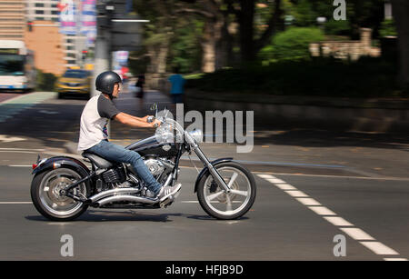 Un homme chevauche son Harley Davidson moto à travers le centre-ville. Le panoramique est devenue à l'arrière-plan. Banque D'Images