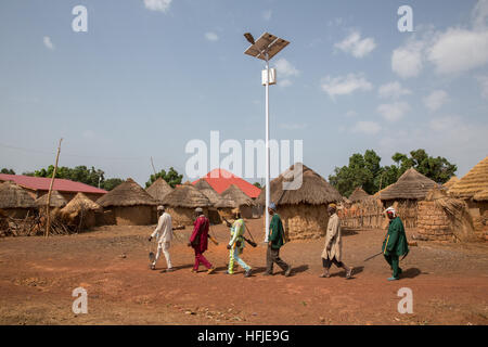 Gbderedou Baranama, Guinée, 2 mai 2015 ; un groupe de chasseurs du village avec leurs fusils à pied passé à énergie solaire nouvellement installé l'éclairage des rues. Banque D'Images