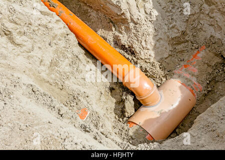 Organisé dans les conduites d'eau en PVC sont assemblés et placés dans la tranchée sur chantier. Banque D'Images
