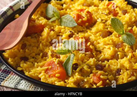 Riz jaune sucré avec des raisins secs et des abricots séchés close-up sur une plaque horizontale. Banque D'Images