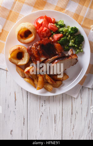 Le rôti du dimanche : porc aux pommes de terre, de légumes et de Yorkshire pudding sur la table. vertical vue d'en haut Banque D'Images