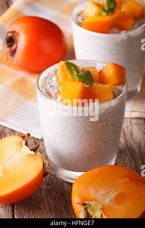 Petit-déjeuner sain : semences chia pudding et persimmon gros plan sur la table verticale. Banque D'Images