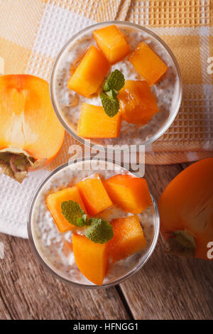 Semences Chia pudding et persimmon gros plan sur la table. vertical vue d'en haut Banque D'Images