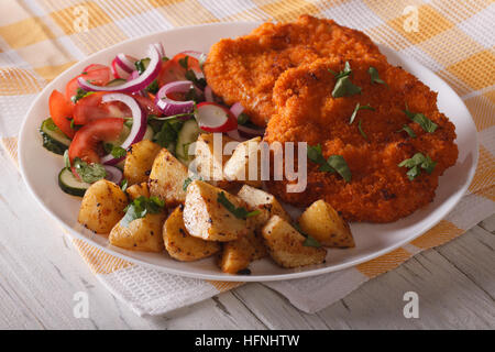 Délicieux schnitzel, pommes frites et salade de légumes sur la table horizontale de près. Banque D'Images