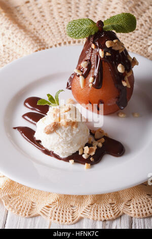 La crème glacée avec des cacahuètes et de poire chocolat coulé sur une plaque verticale. Banque D'Images