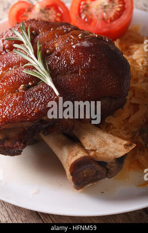 Jarret de porc au four délicieux et de la choucroute macro sur une plaque verticale. Banque D'Images