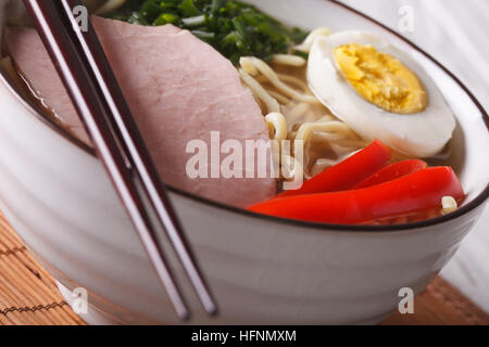 La nourriture japonaise : les nouilles ramen au porc et l'œuf dans un bol horizontal macro. Banque D'Images