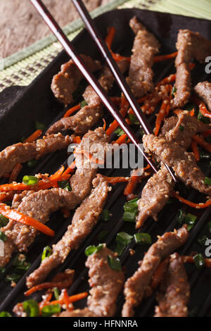 Boeuf bulgogi coréenne avec la carotte et l'oignon sur le gril macro. La verticale Banque D'Images