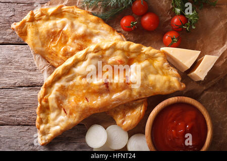 Italian Pizza calzone libre sur un papier et d'ingrédients. vue horizontale de dessus, rustique Banque D'Images