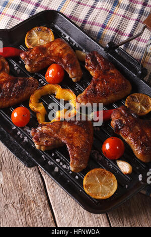 Ailes de poulet grillées avec des légumes dans un poêlon sur la table close-up. La verticale Banque D'Images