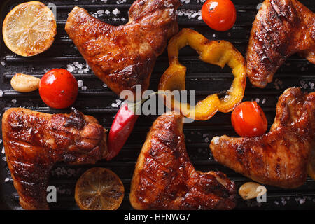 Ailes de poulet avec légumes dans une grille horizontale. macro vue du dessus Banque D'Images