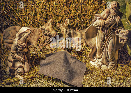 Des statues dans une crèche de Noël, la Sainte Vierge Marie et saint Joseph veille sur le Saint Enfant Jésus dans une crèche dans la paille comme le boeuf et Banque D'Images