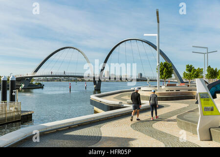 Couple en train de marcher le long de la promenade à Elizabeth Quay avec la passerelle pour piétons à l'arrière-plan, Perth, Western Australia, Australia Banque D'Images