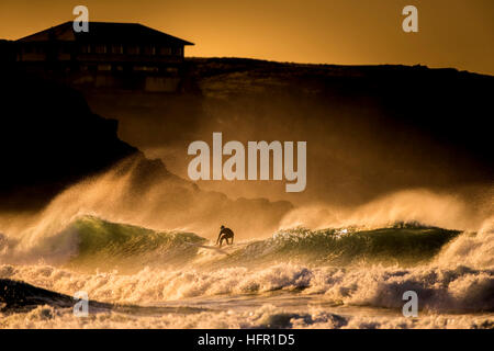 Au cours de surf un spectaculaire coucher du soleil doré à dans Fistral Newquay, Cornwall. UK. Banque D'Images