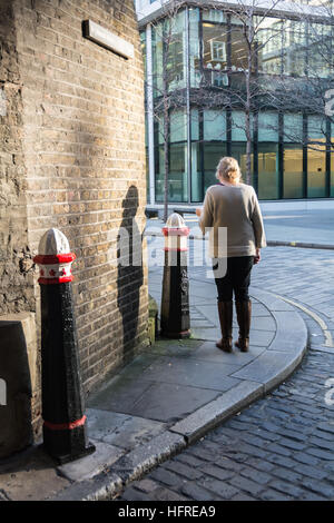 Une femme debout sur un coin de rue à Londres avoir une cigarette Banque D'Images