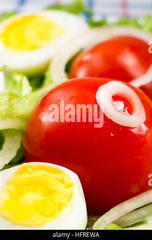 Les tomates cerises et les œufs durs dans une salade de feuilles de laitue, d'huile d'olive et les oignons libre avec une petite profondeur de champ Banque D'Images