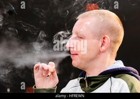 Un jeune homme qui fume un joint de marijuana Banque D'Images